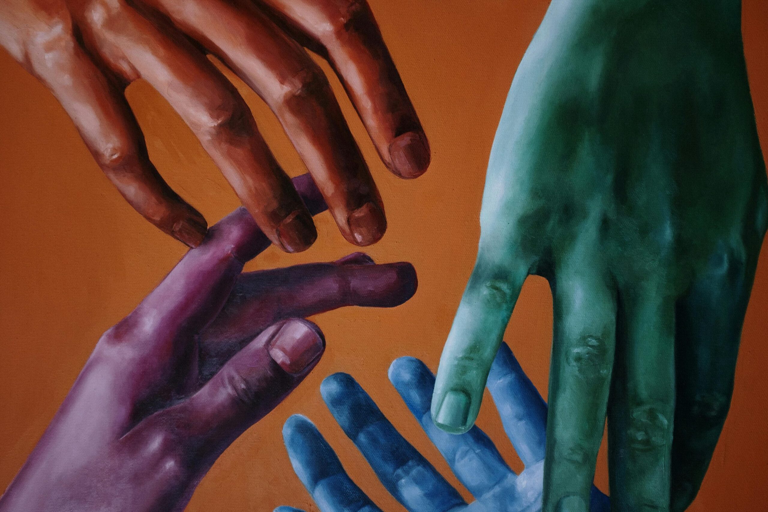 Artistic portrayal of multicolored hands on a vibrant orange background, anyone can get in touch